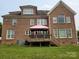 A brick home featuring an outdoor deck, grassy lawn, and mature trees at 8409 Olde Stonegate Ln, Mint Hill, NC 28227