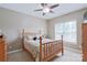 A cozy bedroom featuring a wooden bed frame, ceiling fan, and a window with natural light at 8409 Olde Stonegate Ln, Mint Hill, NC 28227