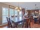An open-concept kitchen and dining space with wooden cabinetry and a dark table set next to bright windows at 8409 Olde Stonegate Ln, Mint Hill, NC 28227