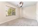 Sunlit bedroom with plush carpeting, ceiling fan, and a window overlooking green trees at 9429 Ridgeforest Dr, Charlotte, NC 28277
