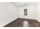 Cozy bedroom showcasing white walls, dark hardwood floors, and natural light from the window at 1112 Concord Ave, Monroe, NC 28110