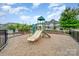 Community playground with a slide and climbing structure surrounded by wood mulch and a black fence at 1126 Roderick Dr, Fort Mill, SC 29708
