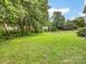 Lush backyard featuring a spacious lawn, mature trees, and natural foliage at 12529 Old Timber Rd, Charlotte, NC 28269