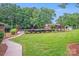 Manicured backyard showcasing a lush lawn, mature trees, an outdoor seating area, and a walkway at 211 Drive Inn Rd, Locust, NC 28097