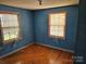 Small bedroom with blue painted walls, hardwood floors, and two windows at 211 Putnam St, Shelby, NC 28152