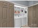 Functional laundry area with washer, dryer, built-in shelving, and dual access doors at 224 Wendover Heights Cir, Charlotte, NC 28211