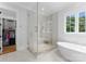Bright bathroom with large glass shower with river rock floor and soaking tub under window at 2941 Forest Park Dr, Charlotte, NC 28209