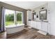 Bright bathroom with a soaking tub under a large window and double sink vanity with wood-look floors at 326 Teeter Rd, Mooresville, NC 28115