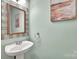 This powder room features a pedestal sink, decorative mirror and soothing paint color at 4502 Magnolia Ridge Dr, Waxhaw, NC 28173