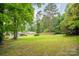 A lush backyard features mature trees, a shed, and a wooden fence, perfect for outdoor activities and privacy at 4533 Gainesborough Rd, Charlotte, NC 28205