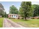 Charming brick home featuring a well-manicured lawn, mature trees, and a cozy front porch, perfect for relaxing outdoors at 4533 Gainesborough Rd, Charlotte, NC 28205