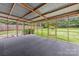A screened in porch with gray carpet looks out onto the lush lawn through walls of screens and a metal awning overhead at 4533 Gainesborough Rd, Charlotte, NC 28205