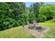 Backyard featuring a stone seating area, lush green grass and mature trees at 4916 Oak Pasture Ln, Charlotte, NC 28269