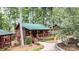 Cozy log cabin with a green metal roof, inviting front porch, and landscaped surroundings at 5002 Samoa Ridge Dr, Lancaster, SC 29270