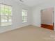 A light-filled bedroom featuring neutral carpeting, large windows, and a doorway leading to another room at 5306 Prosperity View Dr, Charlotte, NC 28269