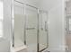 Glass enclosed shower with a built-in seat and grab bars at 5306 Prosperity View Dr, Charlotte, NC 28269