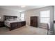 Spacious main bedroom with a dark wood bed frame, a matching dresser and two windows at 585 Gentle Breeze Ln, Rock Hill, SC 29730