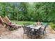 Backyard patio with dining area and lounge chairs surrounded by lush greenery and mature trees at 625 S Magnolia St, Mooresville, NC 28115