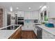 Stylish kitchen featuring white cabinets, stainless steel appliances, marble countertops and a central island cooktop at 625 S Magnolia St, Mooresville, NC 28115