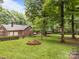 Lush backyard with a fire pit, brick house, and mature trees creates a serene outdoor setting at 635 Timberlane Trl, Salisbury, NC 28147
