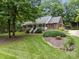 Charming brick home featuring a welcoming front porch, lush landscaping, and mature trees at 635 Timberlane Trl, Salisbury, NC 28147