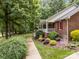 Charming brick home featuring a welcoming front porch, lush landscaping, and mature trees at 635 Timberlane Trl, Salisbury, NC 28147