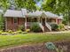 Charming brick home with a welcoming front porch and red shutters nestled in a green lawn at 635 Timberlane Trl, Salisbury, NC 28147