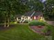 Charming brick home featuring a welcoming front porch, lush landscaping, and mature trees at 635 Timberlane Trl, Salisbury, NC 28147