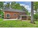 Brick home's backyard with a screened in porch, stone patio, and lush lawn area at 7050 Knightswood Dr, Charlotte, NC 28226