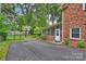 Brick home's backyard featuring a basketball hoop, screened porch, and paved driveway at 7050 Knightswood Dr, Charlotte, NC 28226