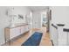 Hallway with a blue rug, blonde wood floors, white console, lamps, and artwork at 790 Herrons Ferry Rd, Rock Hill, SC 29730