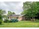 Backyard with brick house, gazebo, deck, green grass, mature trees, and flower beds at 8259 Camelia Ln, Denver, NC 28037