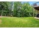 Grassy backyard with mature trees and a glimpse of the home's deck at 9511 Spurwig Ct, Charlotte, NC 28278