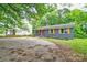 Gray brick home with an orange front door, a paved driveway, and mature trees at 1010 Fallston Rd, Shelby, NC 28150