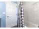 Bathroom featuring a tiled shower with a stylish curtain, next to a white door at 10198 Tintinhull Dr, Fort Mill, SC 29707