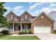 Charming two-story brick home featuring a welcoming front porch, attached two-car garage, and well-maintained landscaping at 10198 Tintinhull Dr, Fort Mill, SC 29707