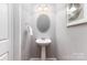 Stylish powder room with pedestal sink, oval mirror, and decorative wall art at 10198 Tintinhull Dr, Fort Mill, SC 29707
