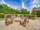 An outdoor patio with brick pavers, wooden seating around a fire pit, and a lush green lawn is perfect for gatherings at 1060 S Lentz Harness Shop Rd, Mount Pleasant, NC 28124
