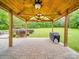 Covered patio with wooden ceiling, fan, and gas grill overlooking the spacious green backyard, perfect for outdoor cooking and relaxation at 1060 S Lentz Harness Shop Rd, Mount Pleasant, NC 28124