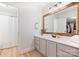 Bright bathroom with a wide mirror, white vanity, and a shower behind a white curtain at 1119 Thornsby Ln, Matthews, NC 28105