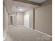 An empty finished basement with neutral walls and carpet, featuring staircase and storage room at 1369 Timberlane Ter, Mooresville, NC 28115