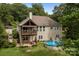 Back of the home with upper level covered deck and lower-level patio, pool and wooded views at 1369 Timberlane Ter, Mooresville, NC 28115