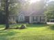 Charming single-story home featuring a well-manicured lawn and flower garden, framed by mature trees, creating a serene setting at 1369 Timberlane Ter, Mooresville, NC 28115