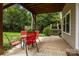 Covered patio with red outdoor seating under a covered patio, steps to a grassy area, and windows at 1369 Timberlane Ter, Mooresville, NC 28115