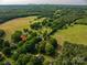 Expansive aerial view displays a lush landscape with a mix of greenery and cultivated fields, indicated by a red arrow at 143 Hallman St, Cherryville, NC 28021
