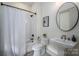 Bright white bathroom with subway tiles, modern fixtures, and a round mirror above the pedestal sink at 1621 Lakefield Cir, Gastonia, NC 28056