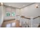 Bright hallway featuring hardwood floors, staircase with wood railings, and large windows with leafy views at 1621 Lakefield Cir, Gastonia, NC 28056