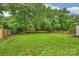 Expansive backyard with lush green lawn, mature trees, a brick wall, and an inviting seating area at 1961 Runnymede Ln, Charlotte, NC 28211