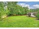 Lush backyard featuring a manicured lawn, mature trees, brick walls, privacy fencing, and a cozy seating area at 1961 Runnymede Ln, Charlotte, NC 28211