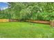 Spacious, well-maintained backyard with a lush lawn, mature trees, brick fencing and a cozy fire pit area at 1961 Runnymede Ln, Charlotte, NC 28211